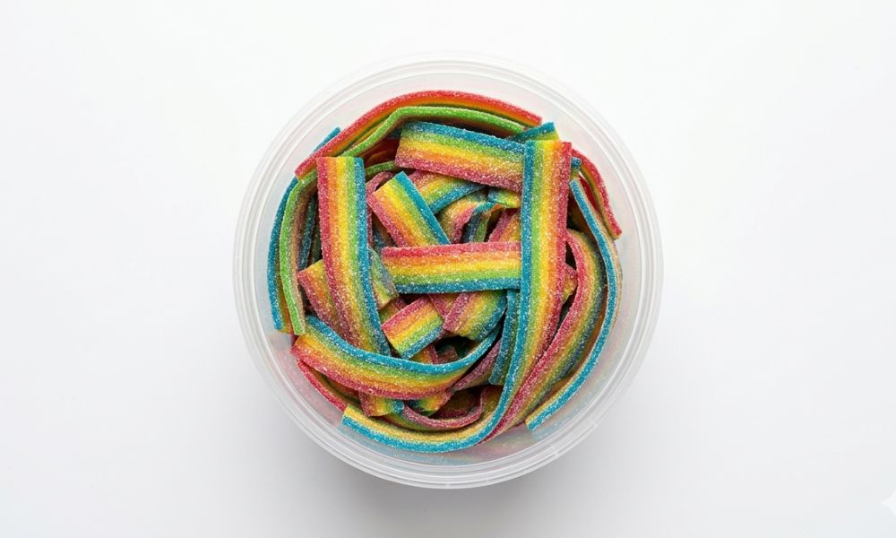 fizzy rainbow belts displayed in a sweet shop tub